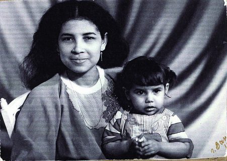 Une jeune femme pose pour le photographe avec sa petite fille sur les genoux.