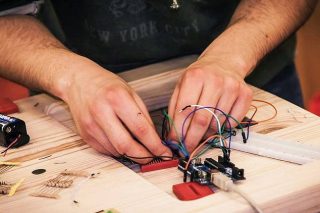 Mains en train de fabriquer un objet avec de l'électronique