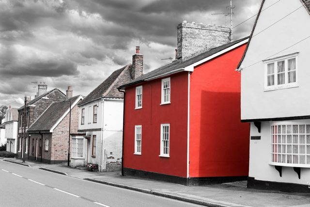 Un alignement de maisons aux façades blanches, une seule est rouge, au milieu.