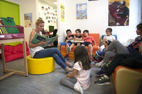 Photo d'une lectrice et d'un groupe d'enfants en bibliothèque.