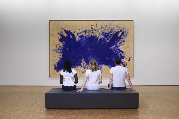 Trois personnes sur un banc assises devant une oeuvre du Centre Pompidou