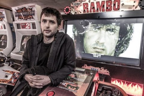 Portrait de Benjamin Nuel accoudé sur une borne d'arcade du jeux Rambo