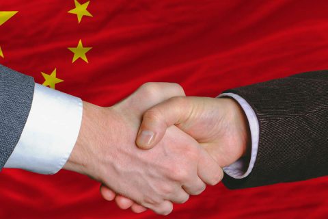 photo d'une poignée de main devant le drapeau chinois