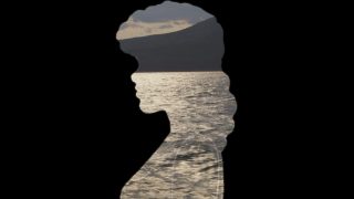 La silhouette d'une femme de profil. Au travers, on voit de l'eau et une montagne.