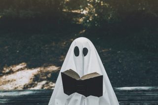 Un fantôme lit un un livre dans un parc.