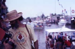 Les Blank en tee-shirt et chapeau, au bord de l'eau en Louisiane.