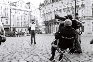 Un homme, assis de dos dans un fauteuil marqué "Claude Lanzmann", fait face à un photographe.
